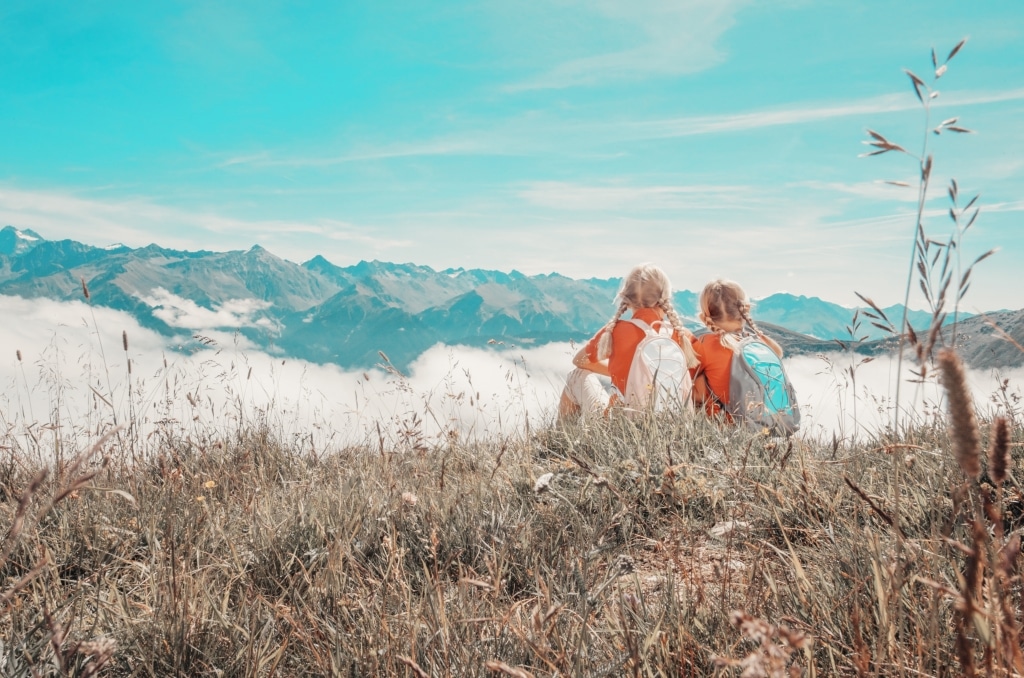 2 Mädchen sitzen am Berg und schauen ins Tal