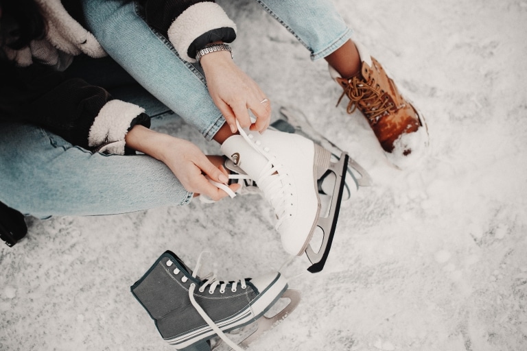 Mädchen zieht sich gerade die Eislaufschuhe an