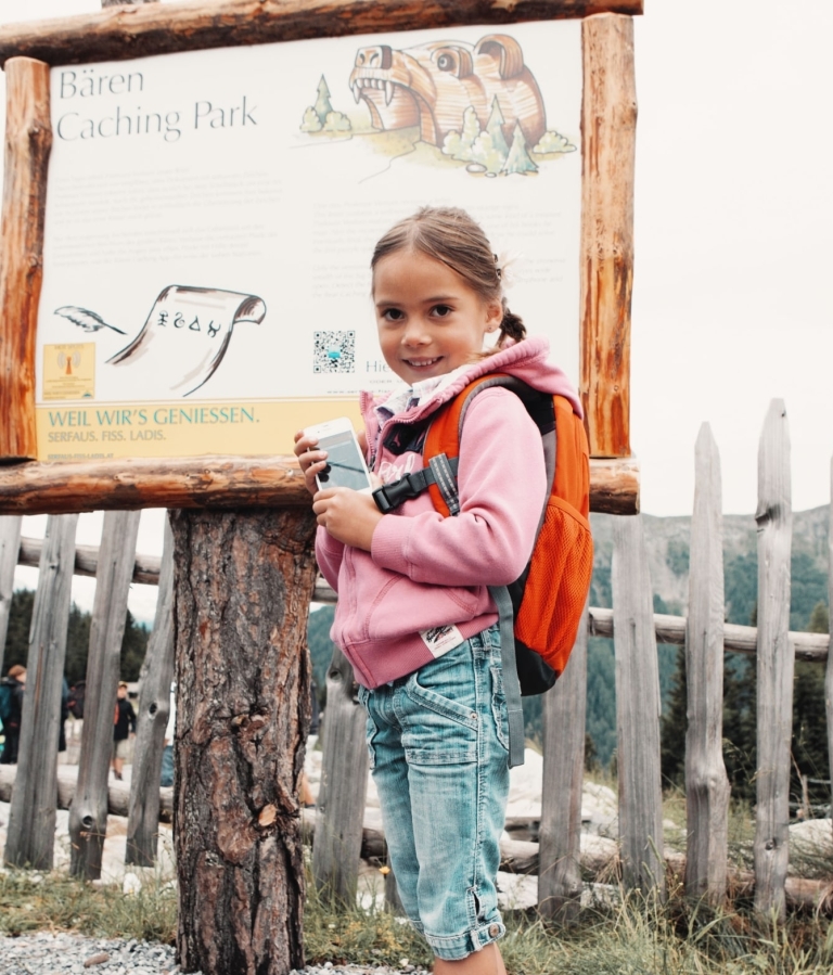Junges Mädchen grinst in die Kamera vor großem Bären Coaching Park