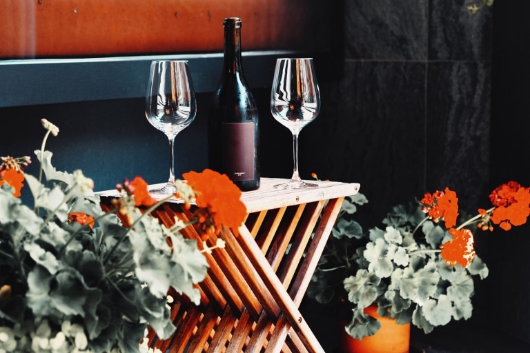 Holztisch mit 2 Weingläsern und einer Flasche Wein
