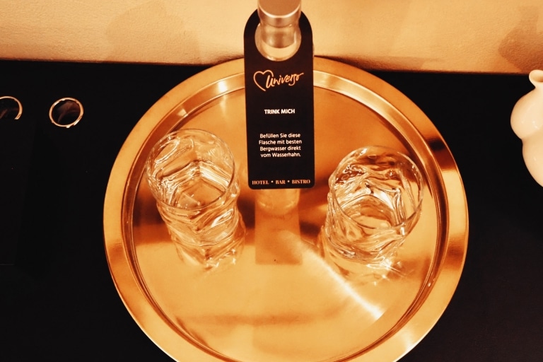 2 Gläser und eine Wasserflasche auf einem goldenen Tablet