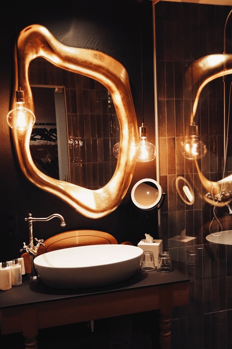 Badezimmer mit goldenem Spiegel und schwarzer Einrichtung